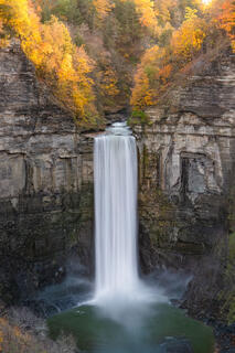 Vertical shot of late light shining through Taughannock Falls during peak foliage.